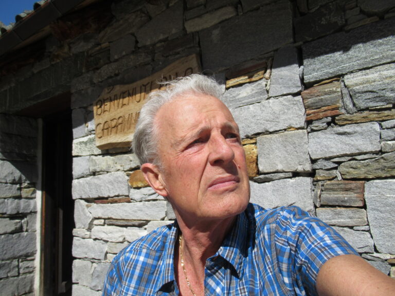 Giuseppe Lacqua all’aperto davanti a una parete in pietra